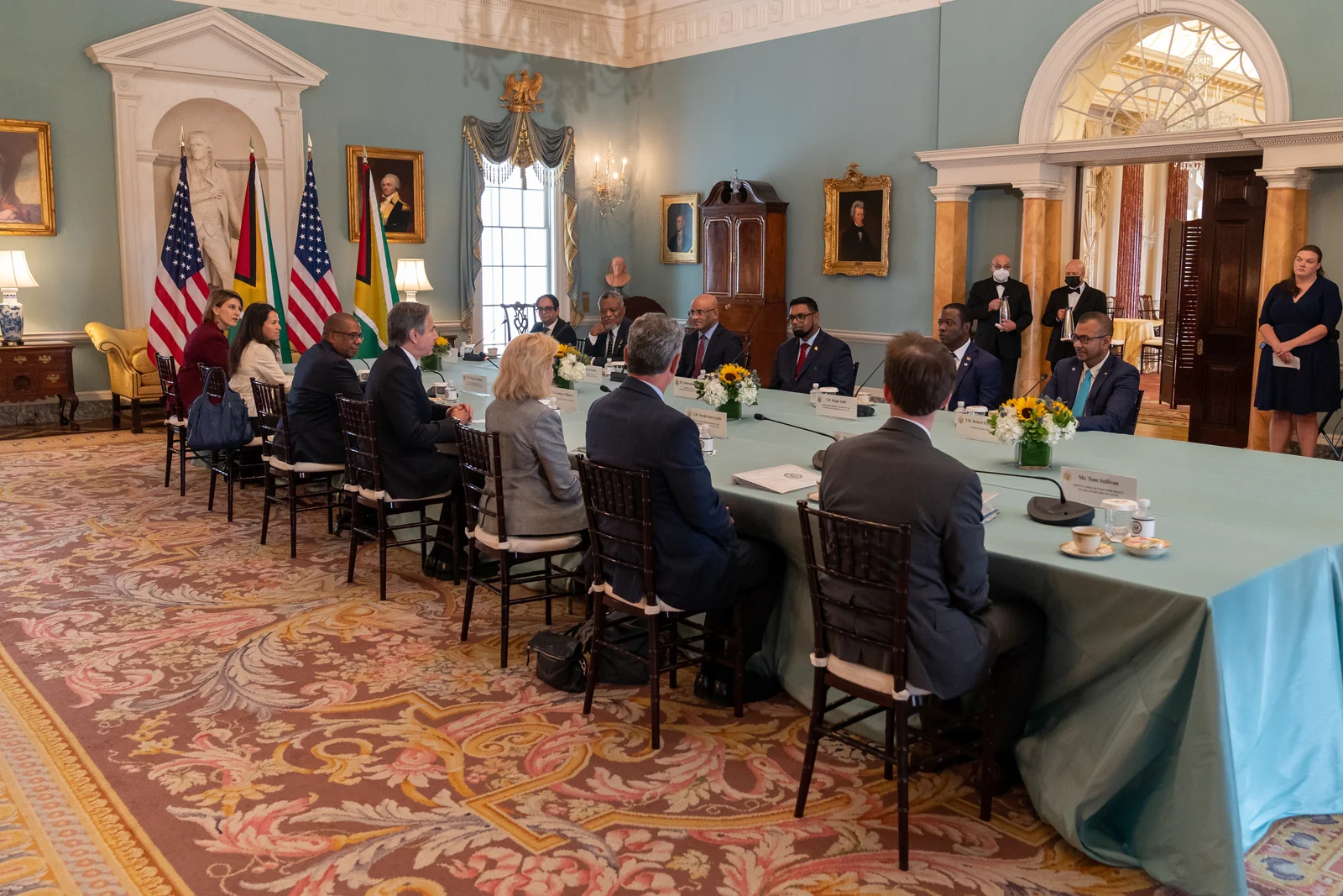 Two Guyana flags appear beside U.S. flags during a meeting between Secretary Antony Blinken and President Irfaan Ali at the U.S. Department of State in Washington, D.C., on July 25, 2022. This photograph documents an indoor diplomatic display.