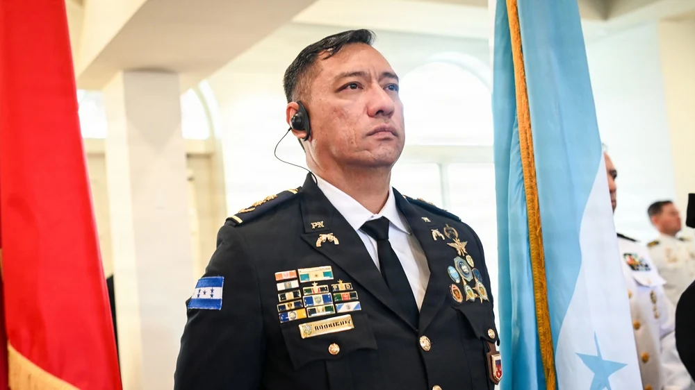 A member of the Honduran delegation stands beside a turquoise rendition of the national flag at the Inter-American Defense College Class 66 Convocation Ceremony, Fort Lesley J. McNair, Washington, D.C., on August 5, 2026. This photograph records actual use at that event, not a nationwide color decree.