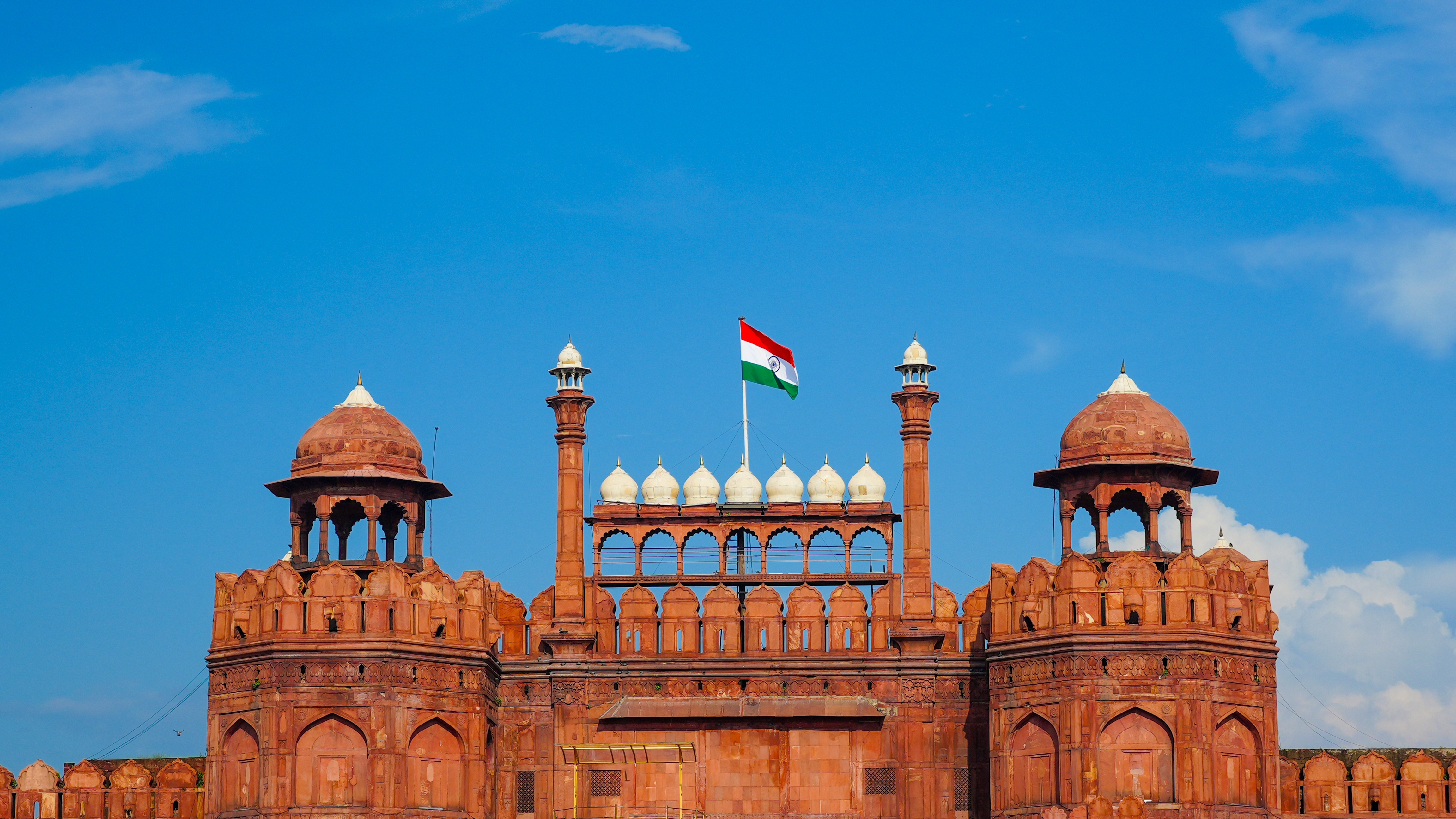 The Red Fort in Delhi under a blue sky with the Indian flag flying above its ramparts